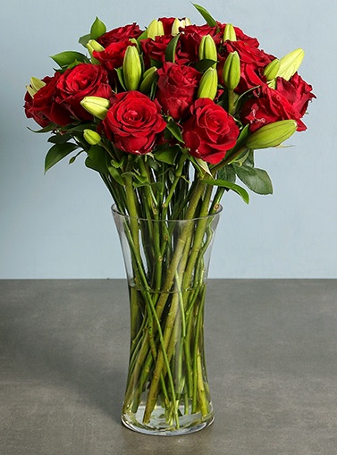 24 red roses and lilies in a clear vase